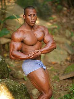 Gorgeous black body builder with perfectly cut muscles flexes in paradise