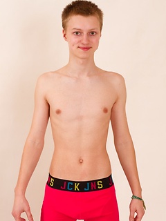 Twink smiles adorably as he poses in his tee shirt and hot pink briefs