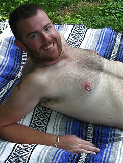 Pierced nipples and cock look sexy on the hairy bearded guy posing on a picnic blanket